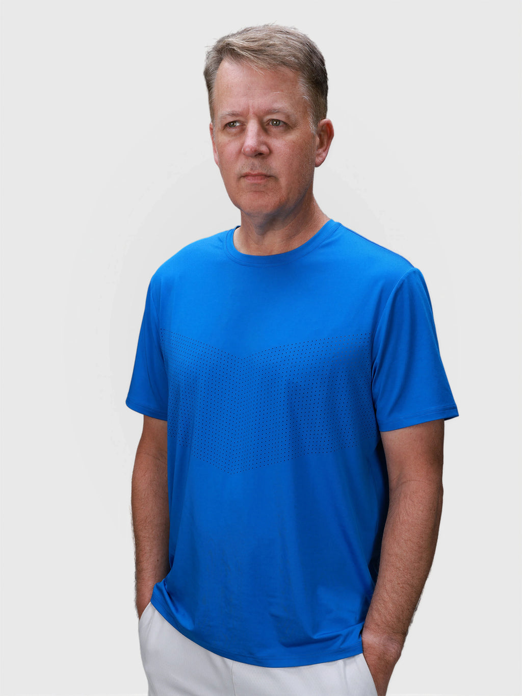 Man wearing royal blue Chevron Tee in pickleball apparel by MUEV with subtle geometric pattern on front